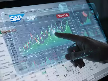 Eine Hand interagiert mit einem holografischen Excel-Interface, das Finanzdaten und Diagramme anzeigt, mit dezenten ERP-Systemlogos. - Foto: über boerse-global.de
