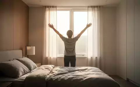Eine Person streckt sich in einem modernen Schlafzimmer dem Morgenlicht entgegen, symbolisiert den Start in einen aktiven Tag. - Foto: über boerse-global.de