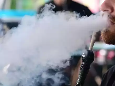 Ein Mann raucht in einer Shisha-Bar eine Wasserpfeife. - Foto: Bernd Weißbrod/dpa