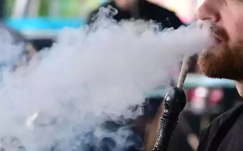 Ein Mann raucht in einer Shisha-Bar eine Wasserpfeife. - Foto: Bernd Weißbrod/dpa