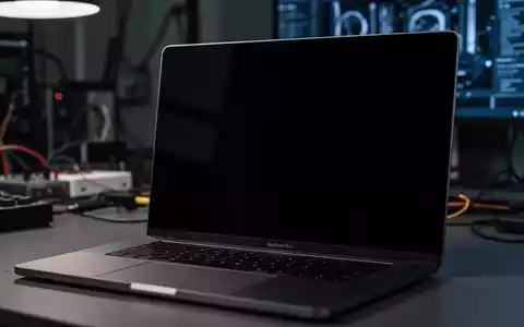 Nahaufnahme eines modernen MacBook Pro mit schwarzem, nicht reagierendem Bildschirm in einem schwach beleuchteten, technischen Umfeld. - Foto: über boerse-global.de