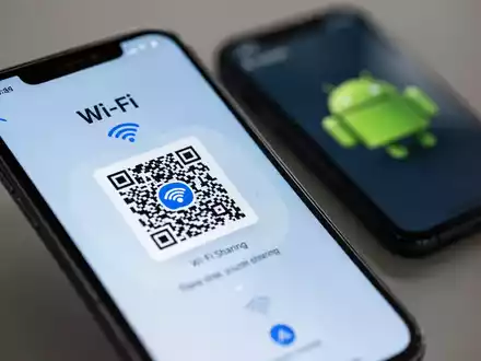 Ein iPhone zeigt einen WLAN-Freigabe-QR-Code, dahinter ein Android-Handy zum Scannen bereit. - Foto: über boerse-global.de