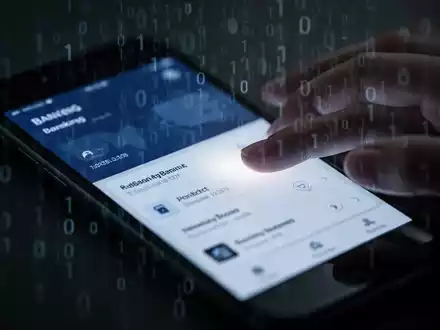 Nahaufnahme eines Smartphones, dessen Bildschirm eine Banking-App mit überlagertem Binärcode und einem unheimlichen Schein zeigt. - Foto: über boerse-global.de