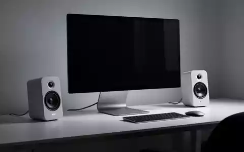 Minimalistische PC-Lautsprecher, die elegant an einem modernen Computermonitor befestigt sind, auf einem aufgeräumten Schreibtisch. - Foto: über boerse-global.de