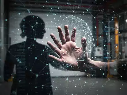 Eine Hand, die in eine schemenhafte, digitale Benutzeroberfläche oder ein Netzwerk greift, das KI darstellt, mit einem industriellen Hintergrund. - Foto: über boerse-global.de