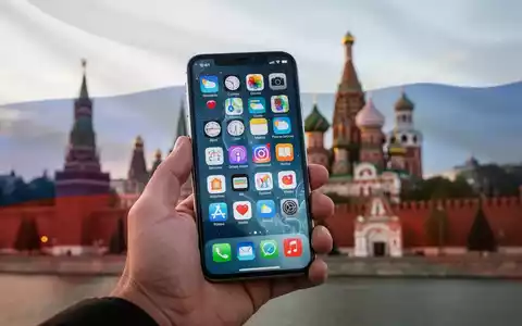Eine Hand hält ein Smartphone mit App-Symbolen, im Hintergrund verschwommen der Moskauer Kreml und eine dezente russische Flagge. - Foto: über boerse-global.de