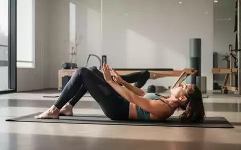 Eine Person führt eine Pilates-Übung auf einer Matte in einem modernen Studio aus, die die Rumpfmuskulatur und Beweglichkeit betont. - Foto: über boerse-global.de