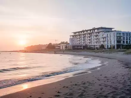 Malerische Küstenlandschaft auf Usedom bei Sonnenaufgang mit einem modernen Rehaklinikgebäude im Hintergrund. - Foto: über boerse-global.de