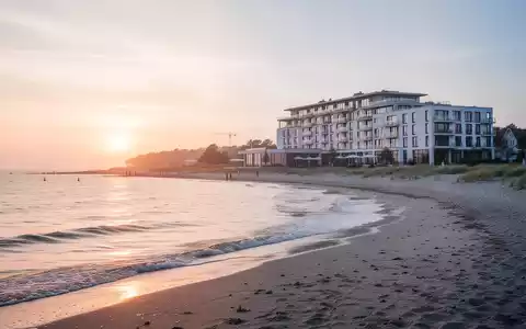 Malerische Küstenlandschaft auf Usedom bei Sonnenaufgang mit einem modernen Rehaklinikgebäude im Hintergrund. - Foto: über boerse-global.de