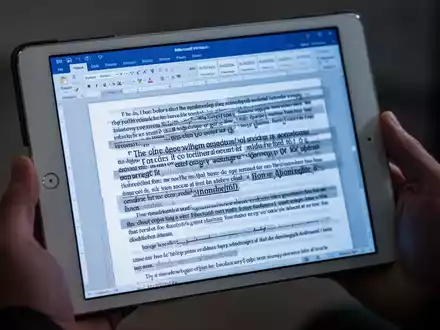 Nahaufnahme eines iPads mit einem Microsoft Word-Dokument mit fehlerhaftem Text und fehlenden Schriftarten, in Händen gehalten. - Foto: über boerse-global.de