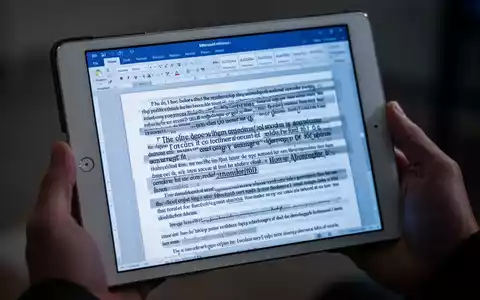 Nahaufnahme eines iPads mit einem Microsoft Word-Dokument mit fehlerhaftem Text und fehlenden Schriftarten, in Händen gehalten. - Foto: über boerse-global.de