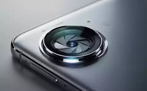 Nahaufnahme einer futuristischen Smartphone-Kamera-Linse mit komplexen inneren Mechanismen und sanftem Glühen auf einem schlanken Metallgehäuse. - Foto: über boerse-global.de