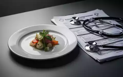 Ein Teller mit einer sehr kleinen Portion Essen neben medizinischen Dokumenten, die eine restriktive DiĂ€t und Therapie symbolisieren. - Foto: ĂŒber boerse-global.de