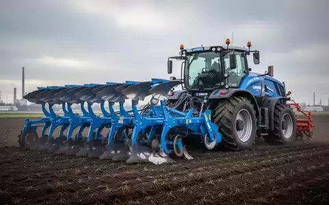 Eine große, moderne blaue Landmaschine steht ungenutzt auf einem Feld unter bewölktem Himmel, symbolisch für Kurzarbeit. - Foto: über boerse-global.de