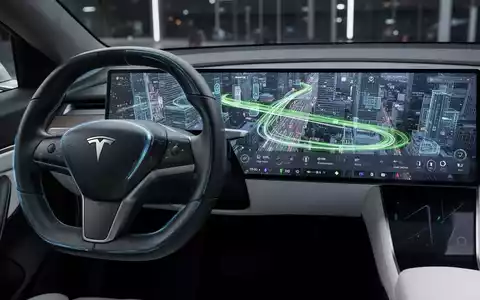Nahaufnahme von Teslas Lenkrad und zentralem Touchscreen mit Full-Self-Driving-Oberfläche in einer urbanen Umgebung. - Foto: über boerse-global.de