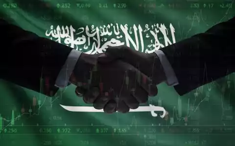 Eine stilisierte Handschlag-Silhouette vor der Flagge Saudi-Arabiens und einem Börsenticker-Overlay, das eine Geschäftspartnerschaft symbolisiert. - Foto: über boerse-global.de