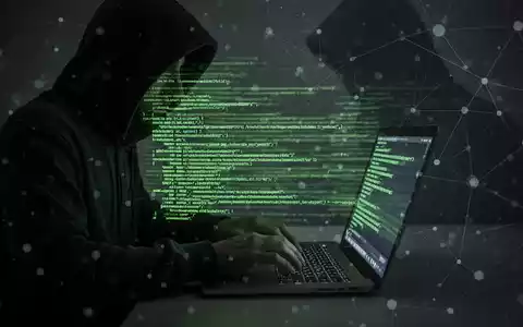 Person in Kapuzenjacke tippt auf Laptop, grün leuchtender Code und digitales Netzwerk-Overlay, symbolisiert Cyberkriminalität. - Foto: über boerse-global.de