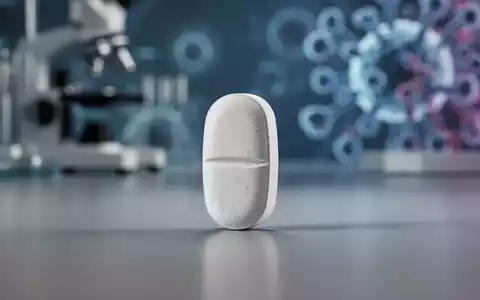 Eine einzelne pharmazeutische Pille liegt auf einer glatten Oberfläche, mit einem verschwommenen Hintergrund aus medizinischer Ausrüstung. - Foto: über boerse-global.de