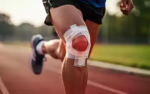 Nahaufnahme des Knies eines Läufers mit Sporttape, das Belastung oder Verletzung andeutet, während er auf einer Strecke läuft. - Foto: über boerse-global.de