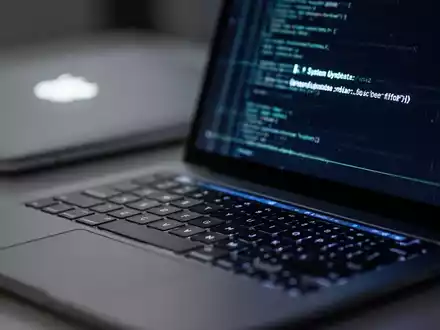 Nahaufnahme einer Laptop-Tastatur mit verschwommenem Hintergrund und leuchtendem Apple-Logo auf dem Bildschirmdeckel, das ein Software-Update darstellt. - Foto: über boerse-global.de