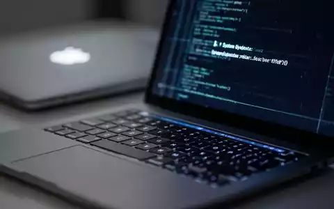 Nahaufnahme einer Laptop-Tastatur mit verschwommenem Hintergrund und leuchtendem Apple-Logo auf dem Bildschirmdeckel, das ein Software-Update darstellt. - Foto: über boerse-global.de