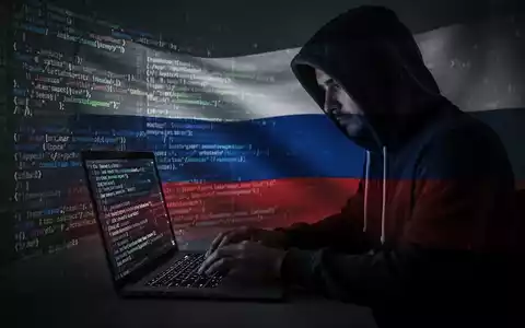 Verschwommene Gestalt in Kapuzenjacke tippt auf Laptop, digitaler Code und dezente russische Flagge auf dem Bildschirm. - Foto: über boerse-global.de