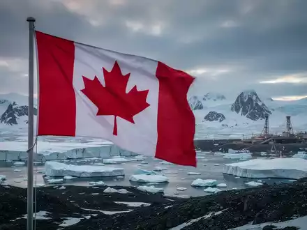 Eine kanadische Flagge weht vor einer rauen, eisigen Landschaft Grönlands mit Bergbauinfrastruktur im Hintergrund. - Foto: über boerse-global.de