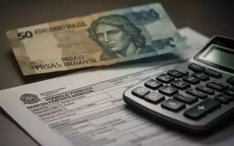 Nahaufnahme einer brasilianischen Real-Banknote, eines Taschenrechners und von Prüfungsdokumenten, die auf finanzielle Unstimmigkeiten hinweisen. - Foto: über boerse-global.de