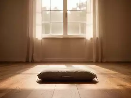 Ein ruhiger Meditationsraum mit einem einzelnen Meditationskissen auf einem Holzboden, beleuchtet von sanftem, warmem Licht. - Foto: über boerse-global.de