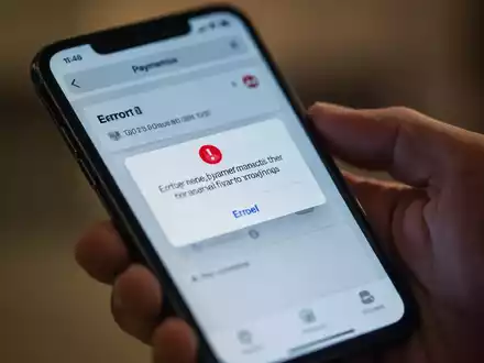 Ein Smartphone-Bildschirm zeigt eine Fehlermeldung bei einer Zahlungstransaktion in einer mobilen App, mit einer unscharfen Hand, die das Gerät hält. - Foto: über boerse-global.de