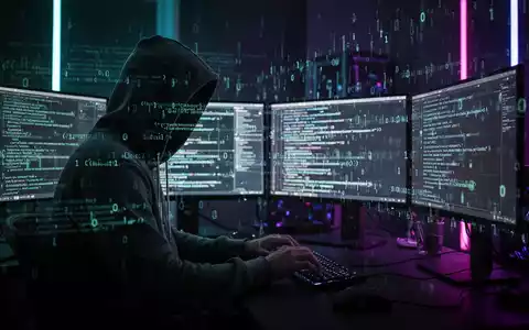 Person in Kapuzenjacke tippt an mehreren Bildschirmen in dunklem Neon-Raum mit Code-Overlays. - Foto: über boerse-global.de