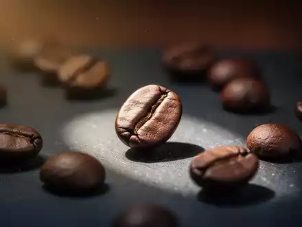 Nahaufnahme von gerösteten Kaffeebohnen auf dunklem Untergrund, eine Bohne ist hell beleuchtet. - Foto: über boerse-global.de