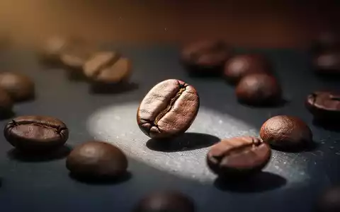 Nahaufnahme von gerösteten Kaffeebohnen auf dunklem Untergrund, eine Bohne ist hell beleuchtet. - Foto: über boerse-global.de