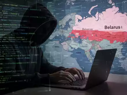 Eine Person im Kapuzenpullover tippt an einem Laptop, mit digitaler Code- und Landkartenüberlagerung im Hintergrund, die Cyberangriffe darstellt. - Foto: über boerse-global.de