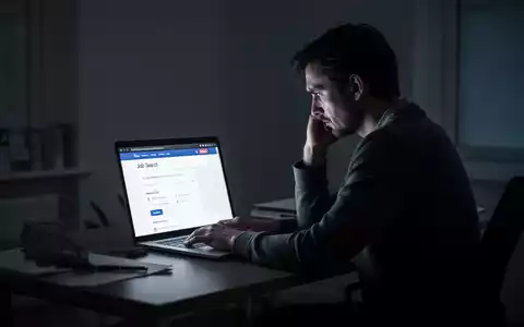 Eine nachdenkliche Person sitzt an einem Schreibtisch vor einem Laptop, der ein Jobportal zeigt, um die psychische Belastung durch lange Jobsuche darzustellen. - Foto: über boerse-global.de