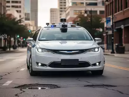 Ein Waymo-Autonavigationsfahrzeug mit sichtbaren Sensoren fährt auf einer Straße in Austin, Texas, mit einem kleinen Schlagloch. - Foto: über boerse-global.de