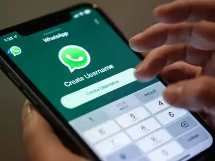 Nahaufnahme eines iPhone-Bildschirms mit der WhatsApp-App und der neuen 'Benutzernamen erstellen'-Funktion. Eine Hand interagiert mit dem Bildschirm. - Foto: über boerse-global.de