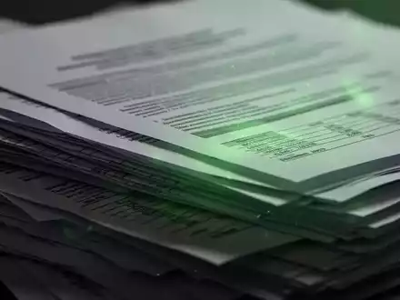 Nahaufnahme eines Stapels Finanzdokumente oder Berichte mit einem grünen Lichtschein, der ESG-Regulierung symbolisiert. - Foto: über boerse-global.de