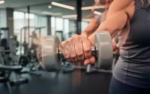 Eine Nahaufnahme der Hand einer älteren Frau, die eine Hantel während des Krafttrainings fest umgreift. - Foto: über boerse-global.de