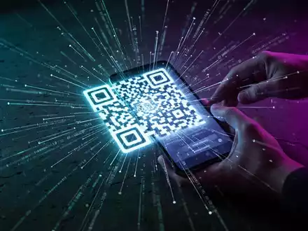 Ein Smartphone scannt einen leuchtenden, schädlichen QR-Code, von dem auf dunklem Hintergrund digitale Datenströme ausgehen. - Foto: über boerse-global.de