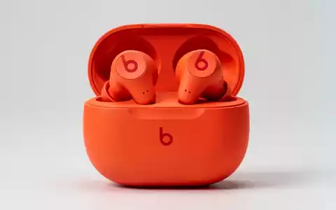 Nahaufnahme von leuchtend orangefarbenen Beats Solo Buds in der Ladehülle mit rotem 'b'-Logo auf sauberem Hintergrund. - Foto: über boerse-global.de