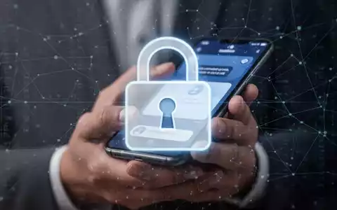 Ein stilisiertes, unscharfes digitales Vorhängeschloss-Symbol über der Nahaufnahme einer Hand, die ein Smartphone mit einer Benachrichtigung hält. - Foto: über boerse-global.de