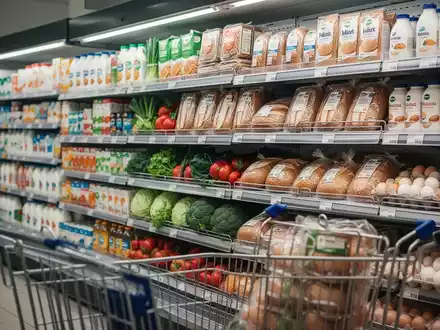 Ein Supermarktgang mit Regalen voller Grundnahrungsmittel wie Milch, Brot, Gemüse und Eier, beleuchtet von warmem Licht. - Foto: über boerse-global.de