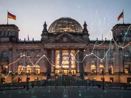 Das Reichstagsgebäude bei Sonnenuntergang, mit abstrakten Linien und digitalen Überlagerungen, die Daten und Wirtschaftssymbole darstellen. - Foto: über boerse-global.de