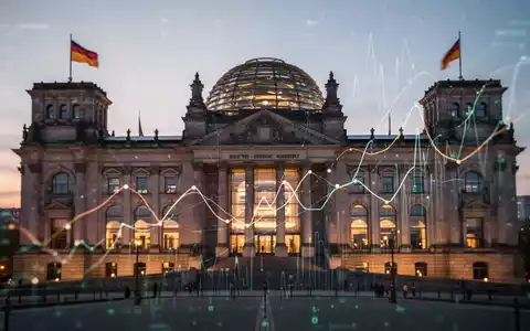 Das Reichstagsgebäude bei Sonnenuntergang, mit abstrakten Linien und digitalen Überlagerungen, die Daten und Wirtschaftssymbole darstellen. - Foto: über boerse-global.de