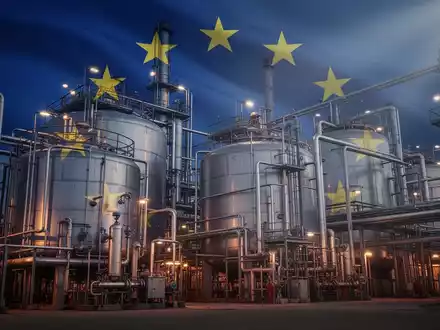 Eine stilisierte Chemieanlage mit großen Industriebehältern und komplexen Rohrleitungen unter dramatischem Licht, im Hintergrund die EU-Flagge. - Foto: über boerse-global.de