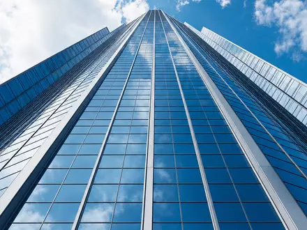 RWE AG (DE0007037129) zeigt einen modernen Glasturm-Hauptsitz aus Froschperspektive mit reflektierender Fassade vor blauem Himmel - Foto: THN