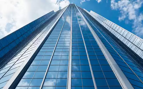 RWE AG (DE0007037129) zeigt einen modernen Glasturm-Hauptsitz aus Froschperspektive mit reflektierender Fassade vor blauem Himmel - Foto: THN