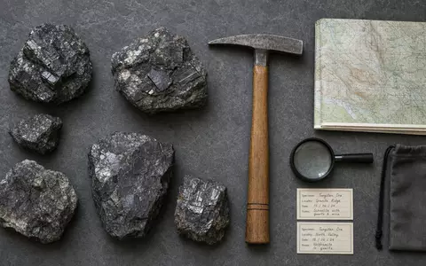 Almonty Industries Inc Wolframerz CA0203987072 als Flatlay mit Geologen-Hammer, Lupe und Geländekarte - Foto: THN