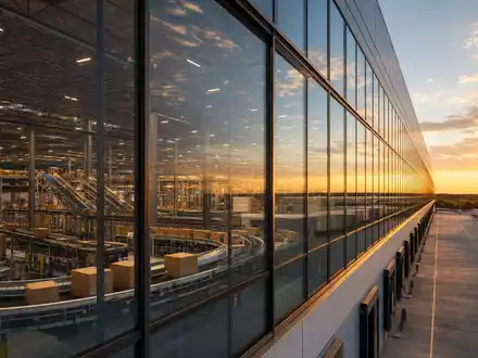 Zalando SE (DE000ZAL1111) – modernes Logistikzentrum mit großer Glasfassade und sichtbaren Förderbändern im Inneren - Foto: THN